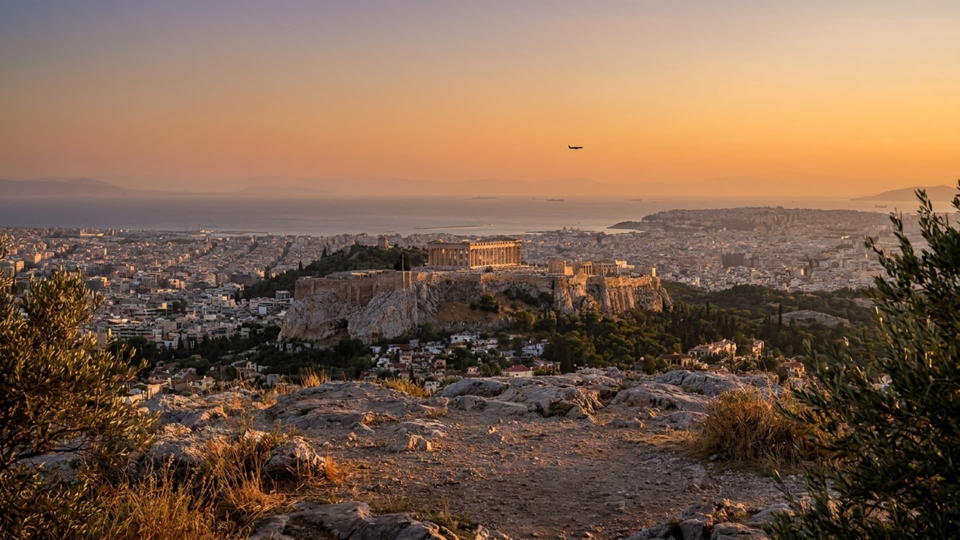 Golden-hour view over Athens with the Acropolis and the Aegean coast beyond, evoking a private jet arrival to Athens, Greece
