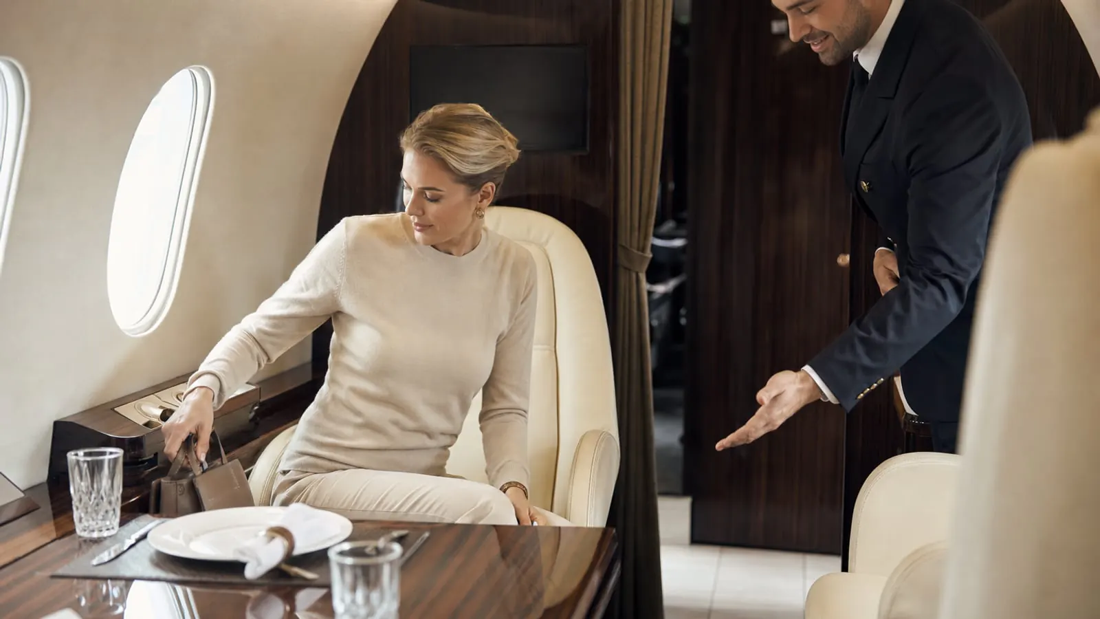 Discreet private jet cabin etiquette moment with traveler settling in and crew offering assistance